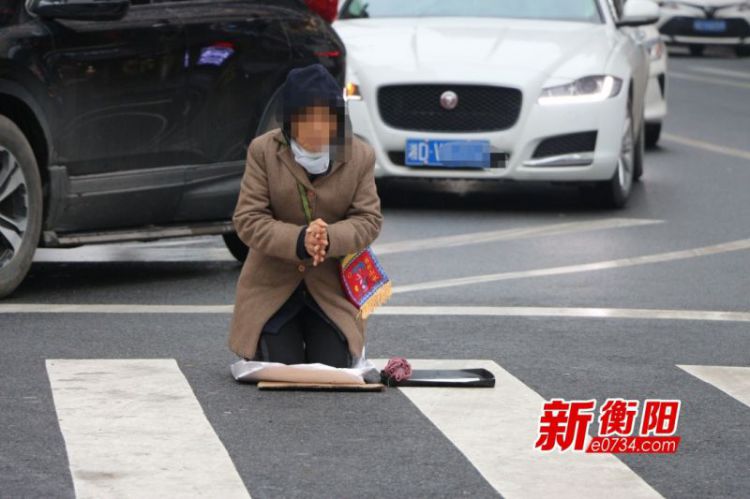 一女子闹市十字路口跪地乞讨车来车往惊险万分