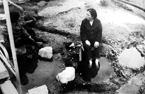 汤岗子温泉80年代老照片：女子把自己埋入泥里坐着水坑前泡脚